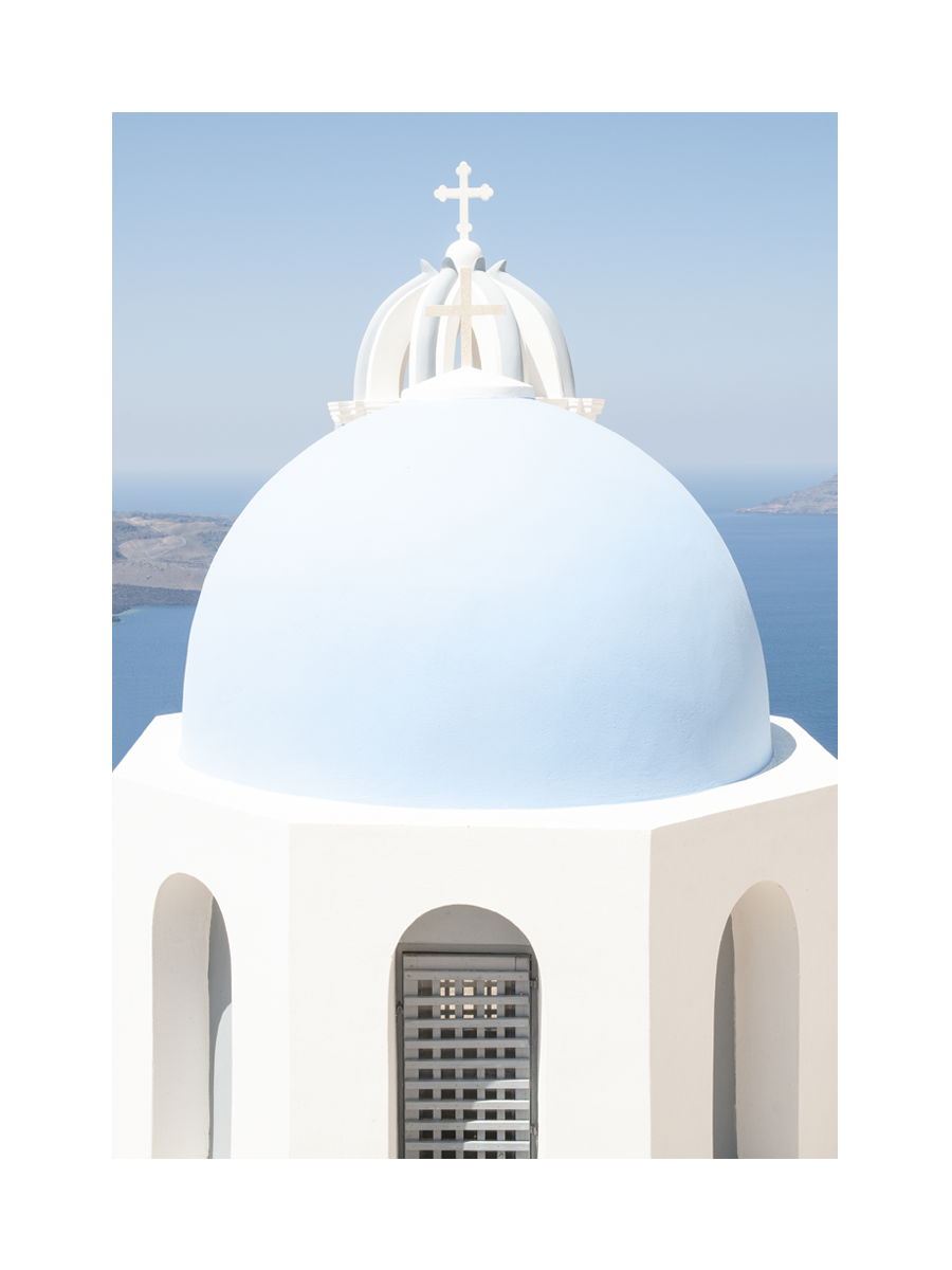Blaue Kuppel einer Kirche auf Santorini mit Meer im Hintergrund.