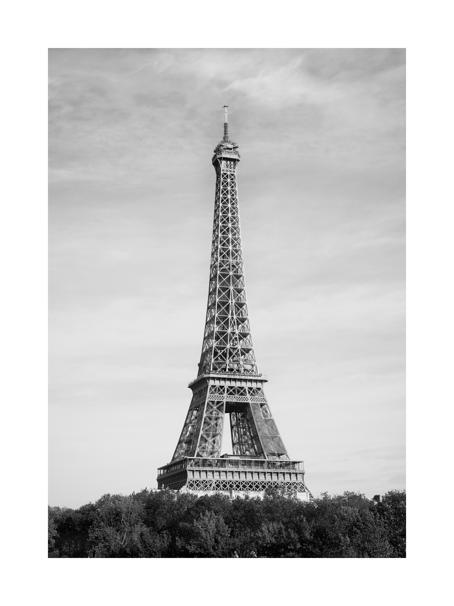 Schwarzweiß-Fotografie des Eiffelturms mit Himmel im Hintergrund.
