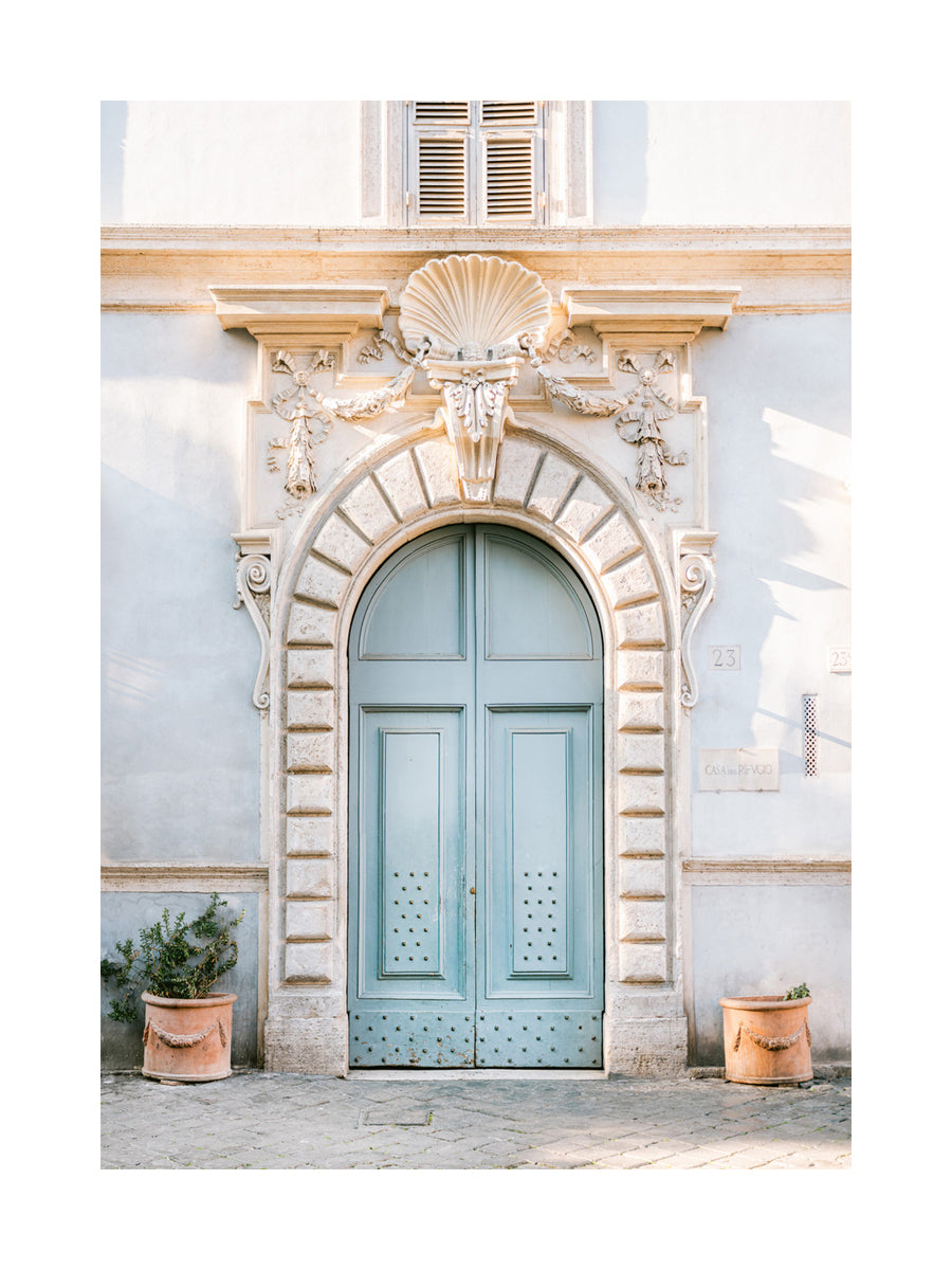 Fotografie einer blauen Tür mit dekorativer Architektur und Pflanzen in Terrakottatöpfen.