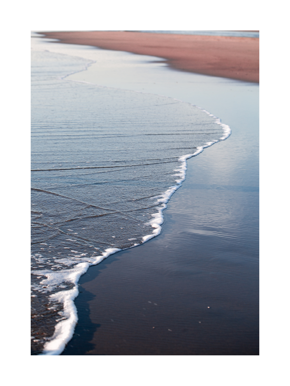 Fotografie von Wellen, die an den Strand rollen.