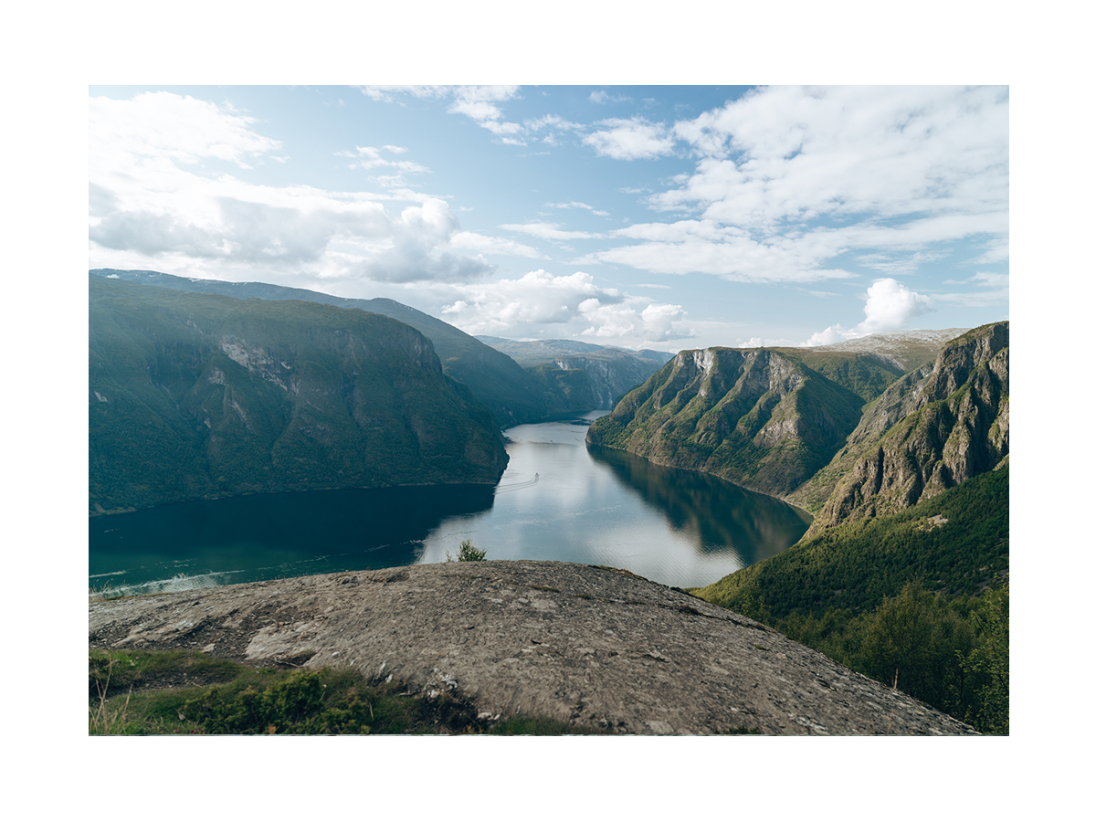 Fotografie des Aurlandsfjords in Norwegen mit blauem Wasser und grünen Bergen.