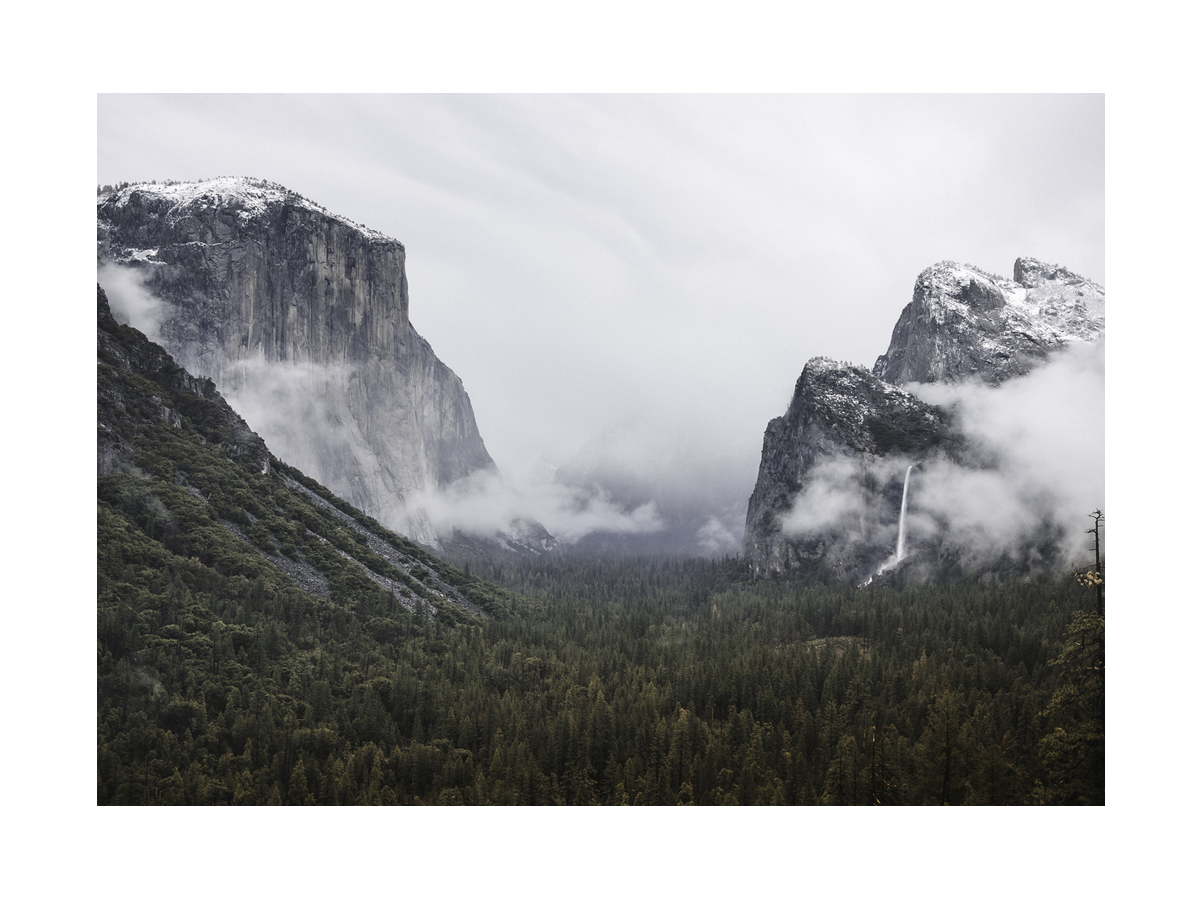 Fotografie des Yosemite-Tals mit Felsformationen und Wasserfall im Nebel.