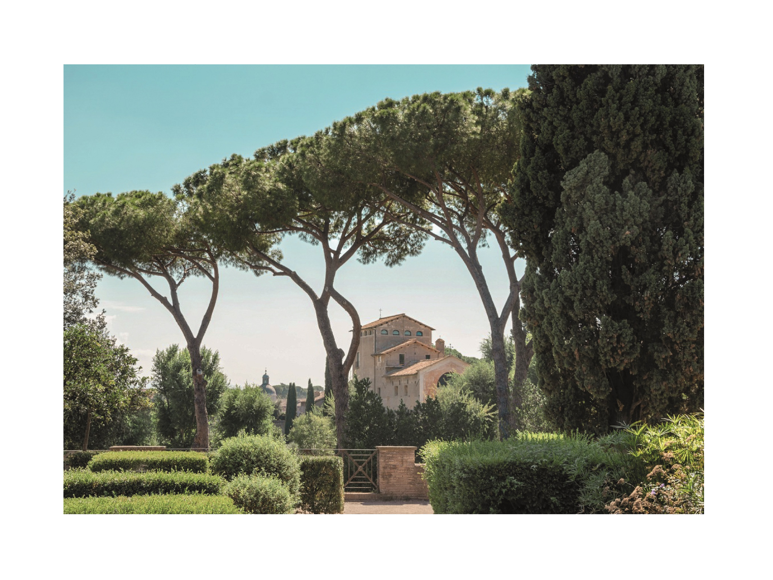 Fotografie einer Villa in einem grünen Garten mit Bäumen und blauem Himmel.