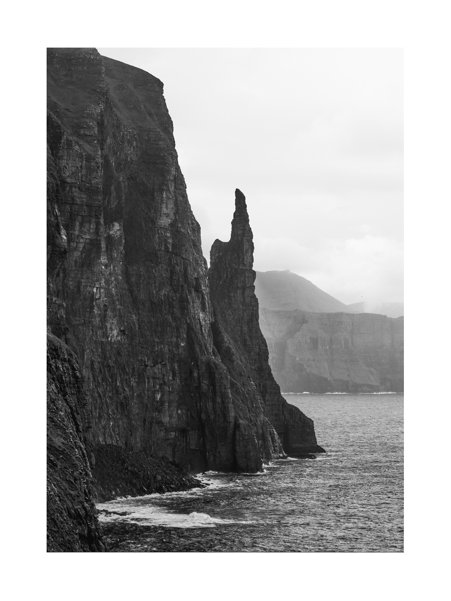 Schwarz-weiß-Fotografie von Klippen und Meer auf den Färöer-Inseln.