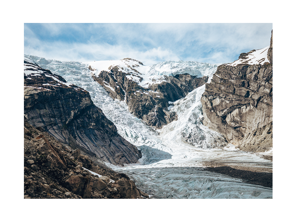 Fotografie eines Gletschers zwischen schneebedeckten Bergen.