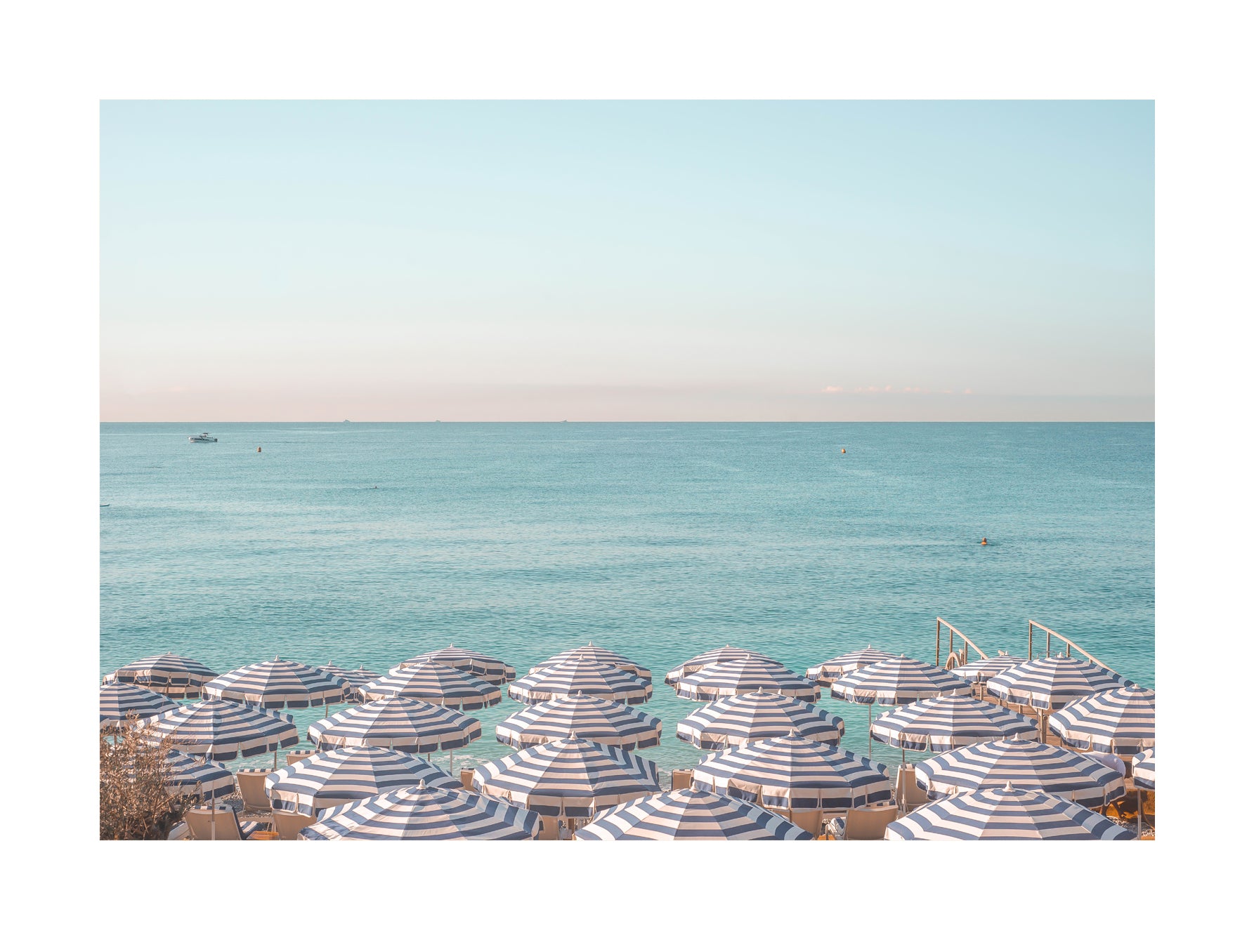 Fotografie von gestreiften Sonnenschirmen am Strand mit Meer und klarem Himmel.