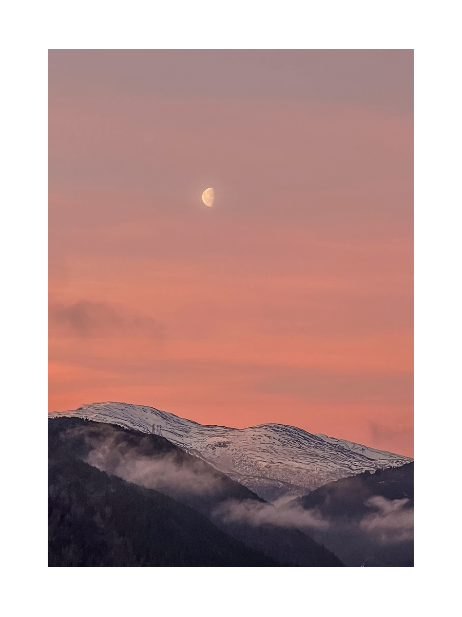 Fotografie des Mondes über schneebedeckten Bergen bei Sonnenuntergang.