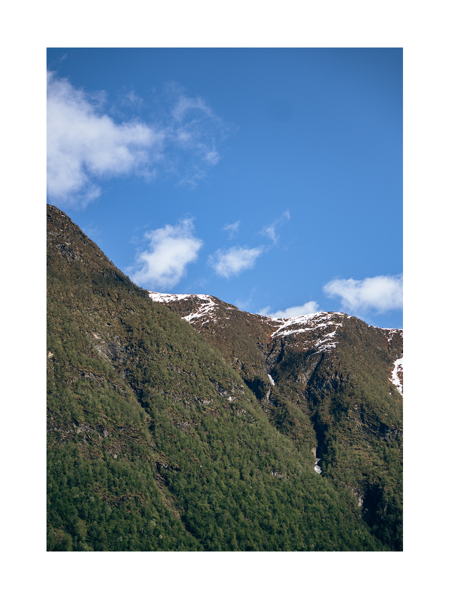Fotografie der Spitze eines Berges mit blauem Himmel und Wolken im Hintergrund.