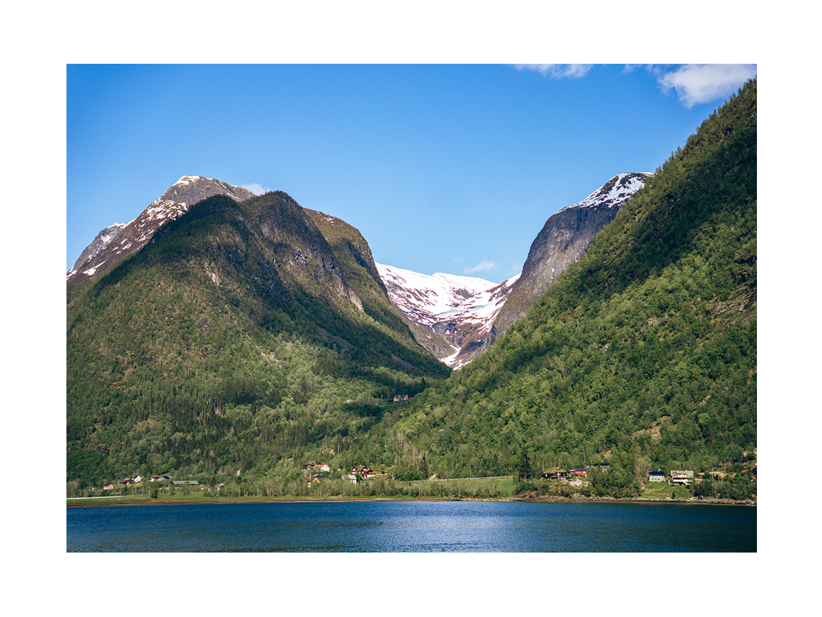 Fotografie von schneebedeckten Bergen in Norwegen mit einem See und Dörfern im Vordergrund.