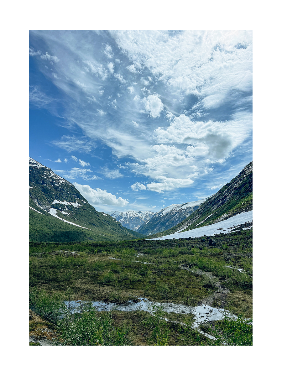 Landschaft in Norwegen mit grünen Bergen und blauem Himmel.
