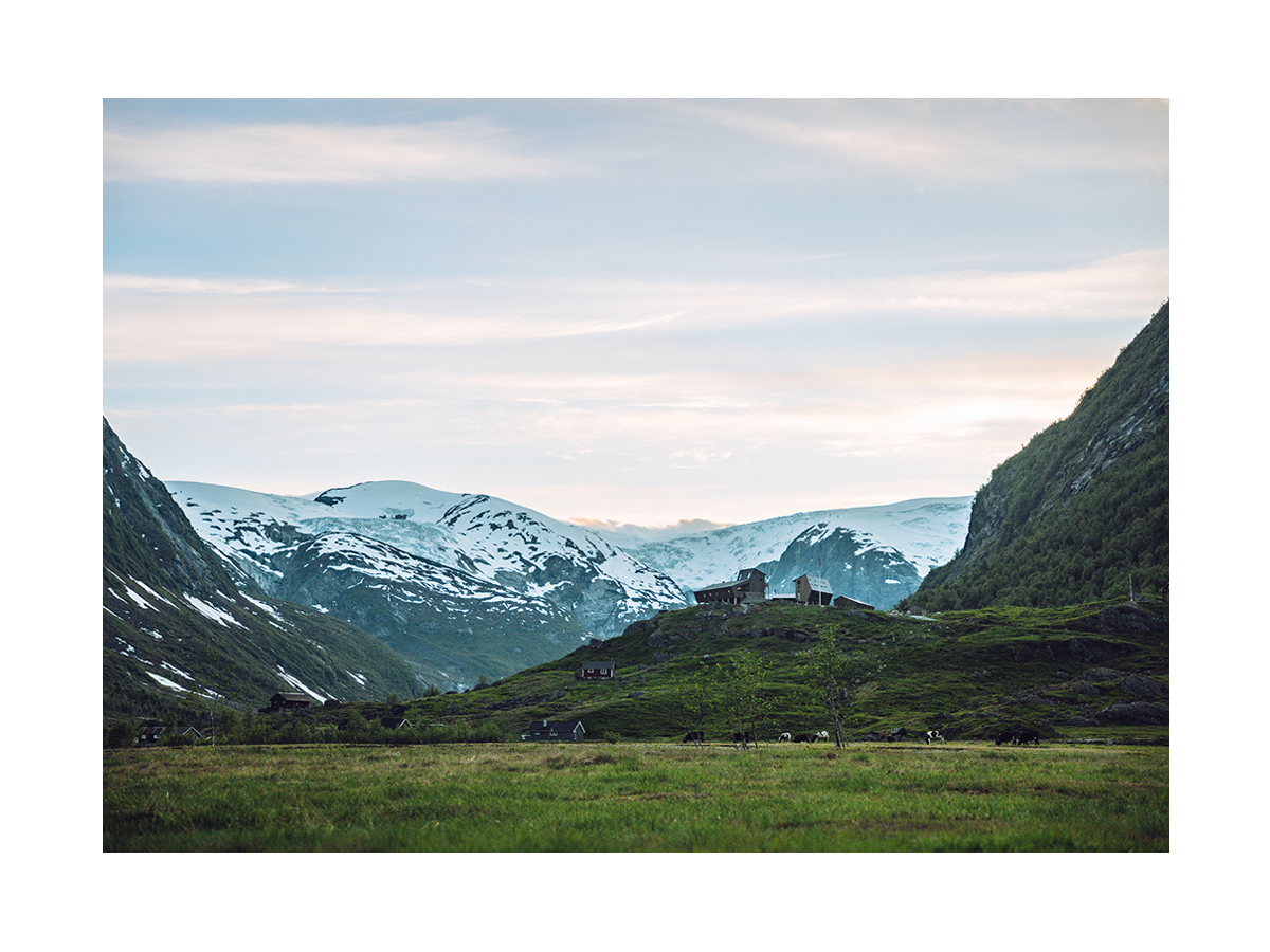 Fotografie von schneebedeckten Bergen mit einem Tal und einem kleinen Dorf im Vordergrund.