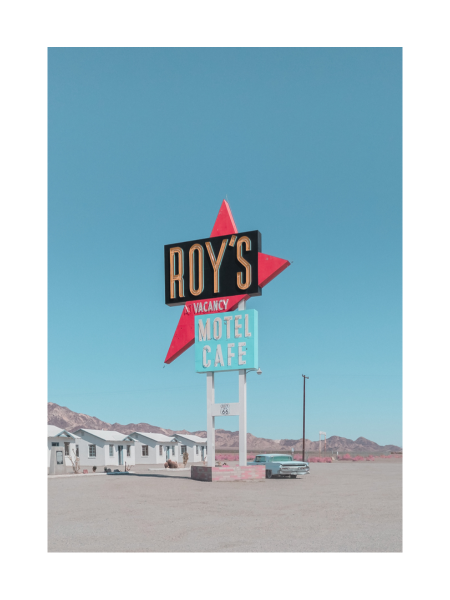 Poster mit dem Schild von Roy's Motel Cafe in der Wüste unter blauem Himmel.