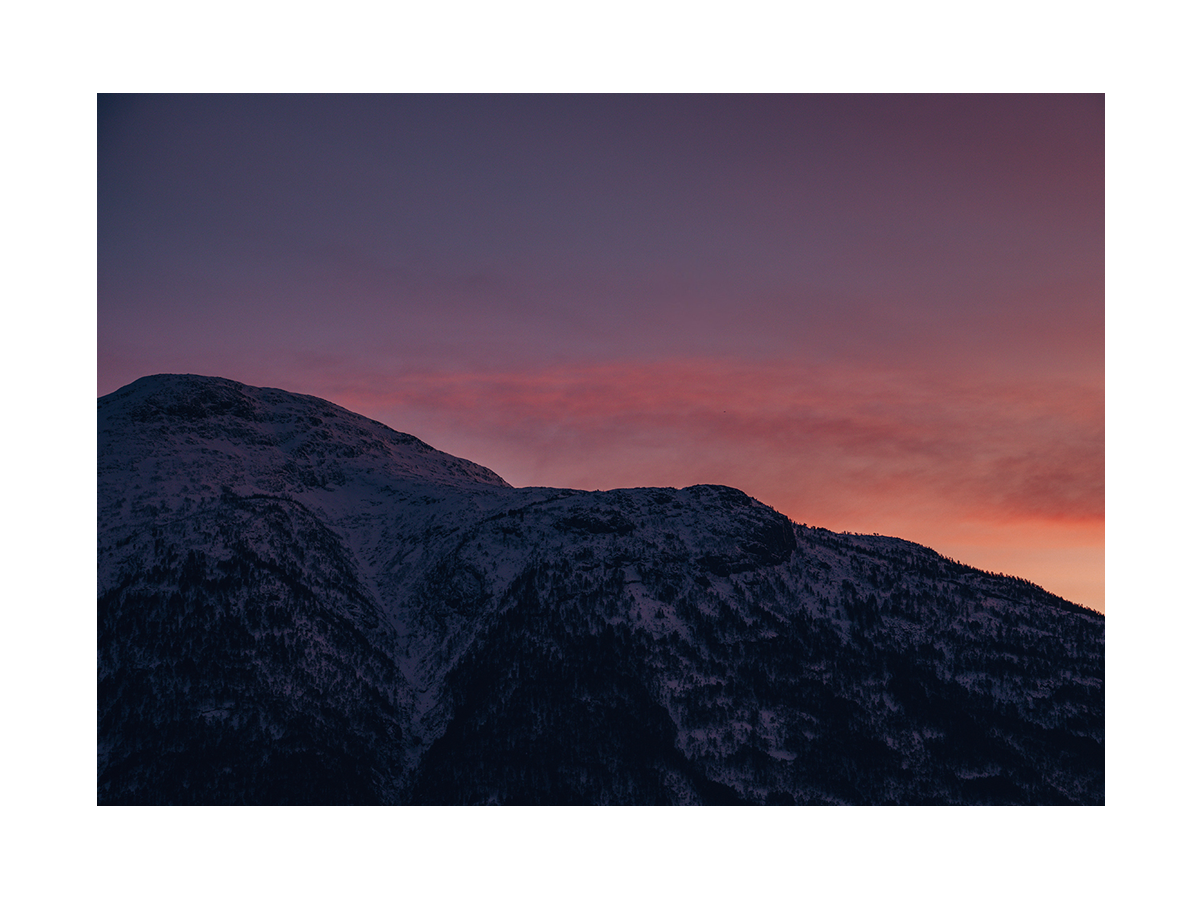 Berglandschaft bei Sonnenuntergang mit rosa und orangefarbenem Himmel.