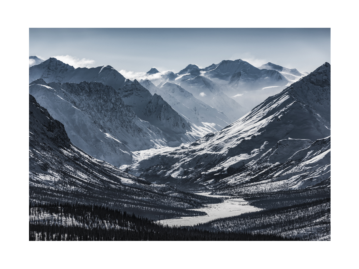 Fotografie von schneebedeckten Bergen und einem Tal.