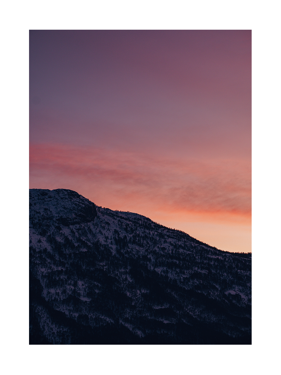 Berggipfel vor einem Sonnenuntergangshimmel mit rosa und orangefarbenen Tönen.