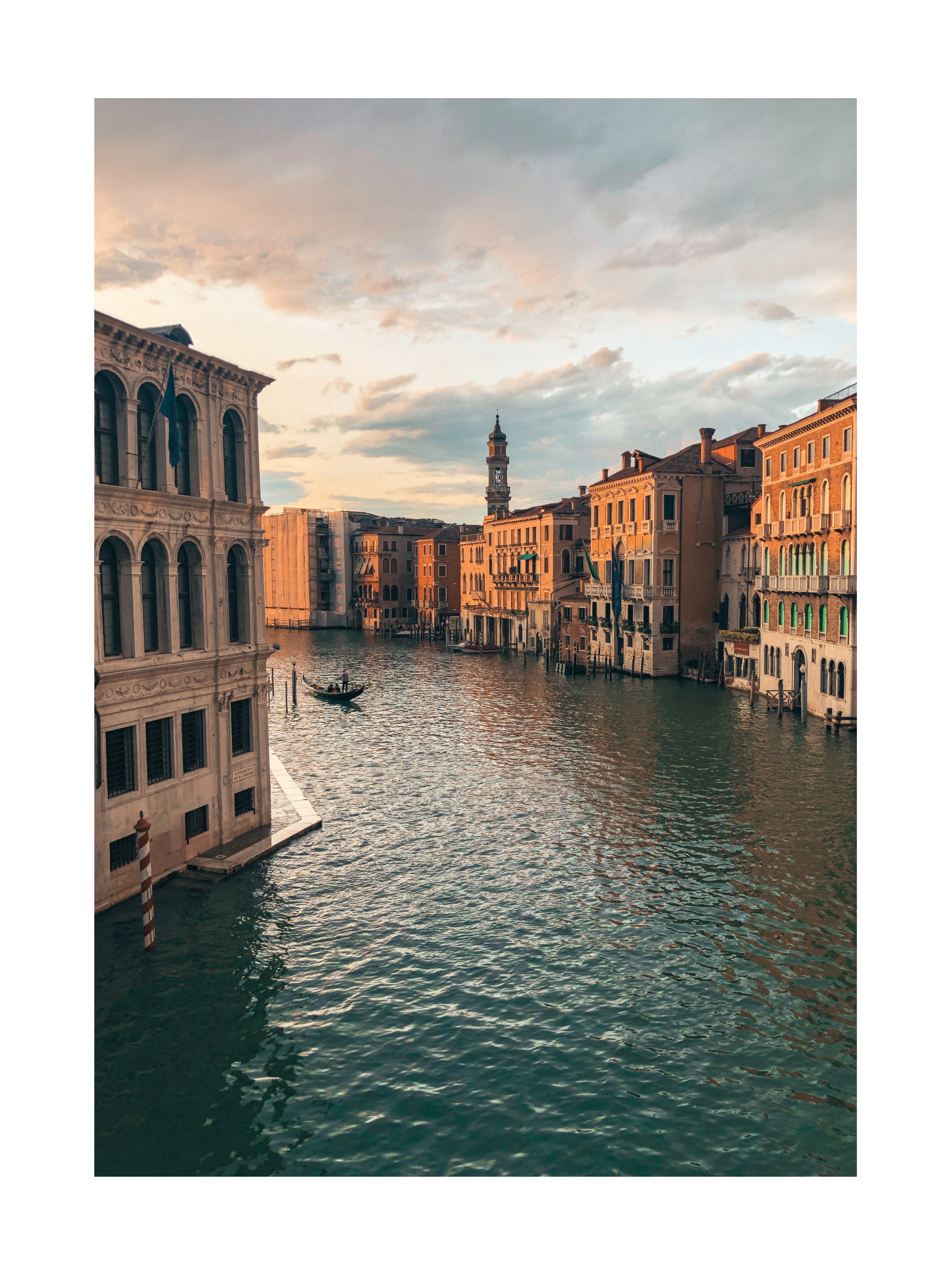 Fotografie eines Kanals in Venedig bei Sonnenuntergang mit historischen Gebäuden und einer Gondel.