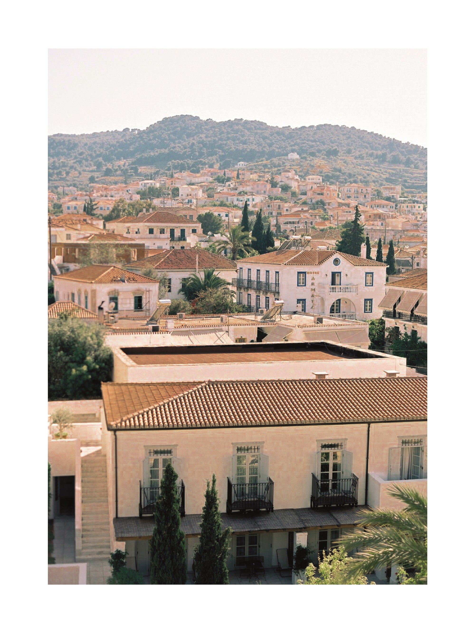 Fotografie von einer mediterranen Stadt mit Bergen im Hintergrund.