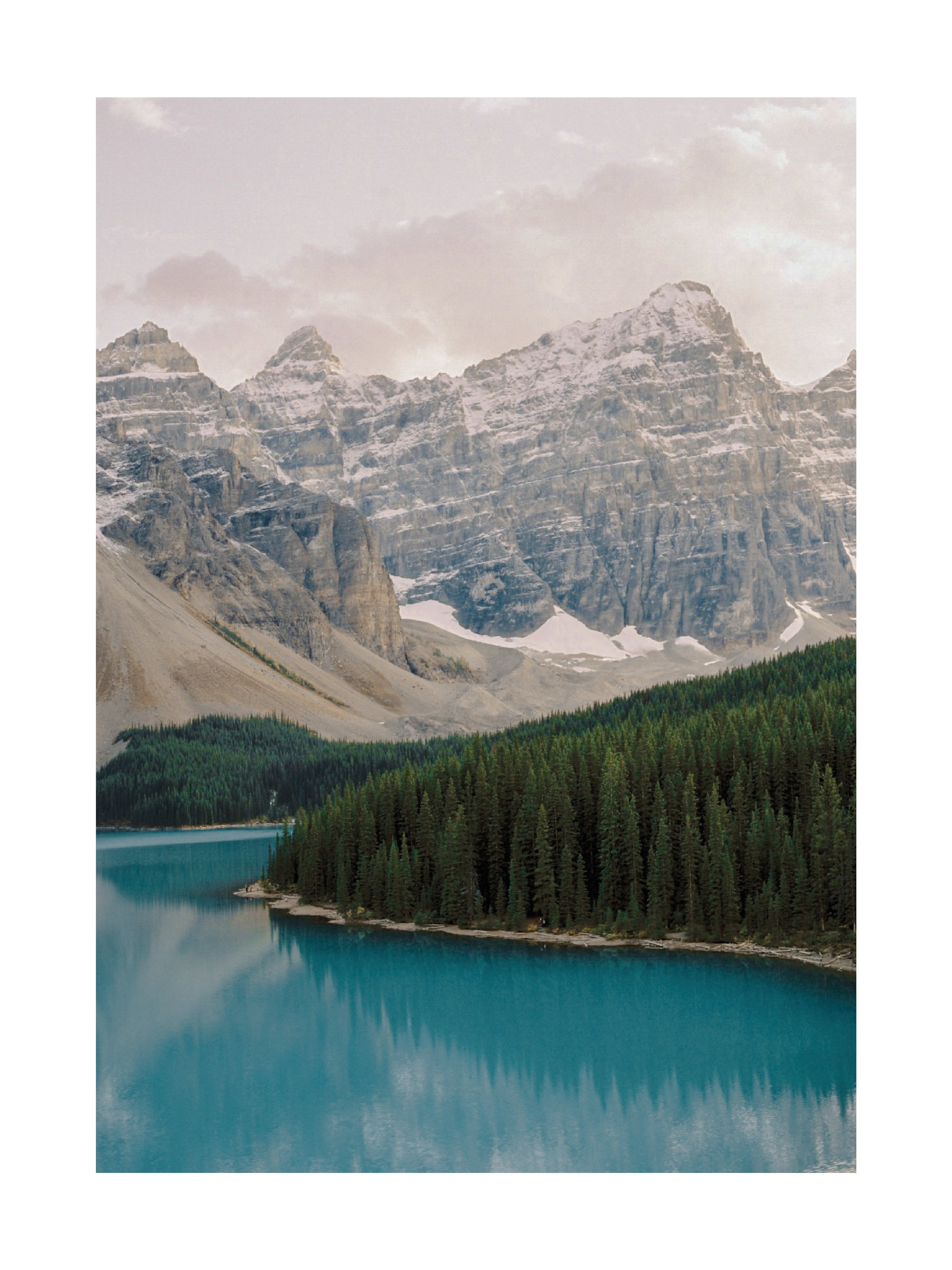 Fotografie von Moraine Lake mit blauem See, Wald und schneebedeckten Bergen.