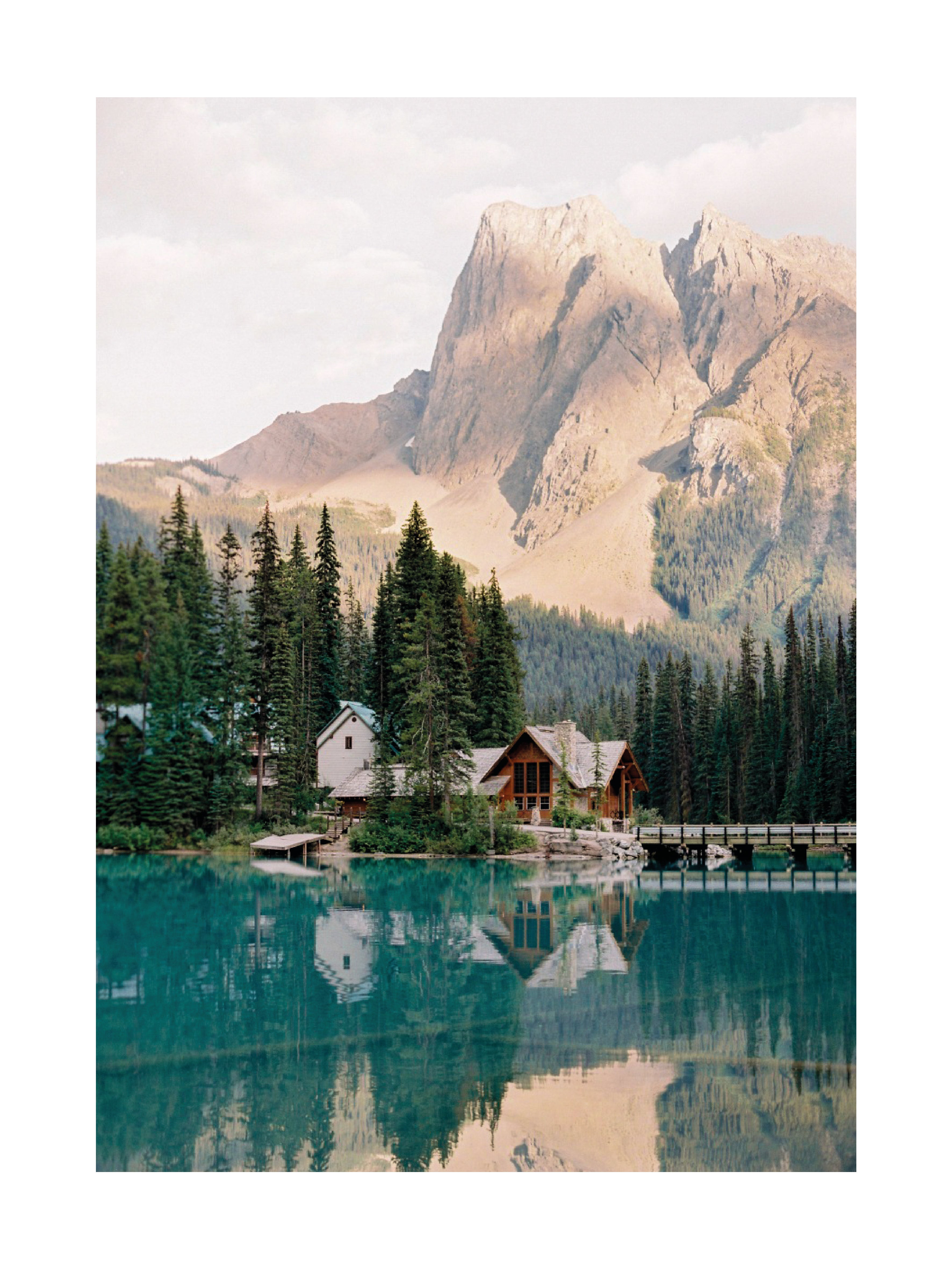 Fotografie von Häusern und Bäumen an einem See mit einem Berg im Hintergrund.