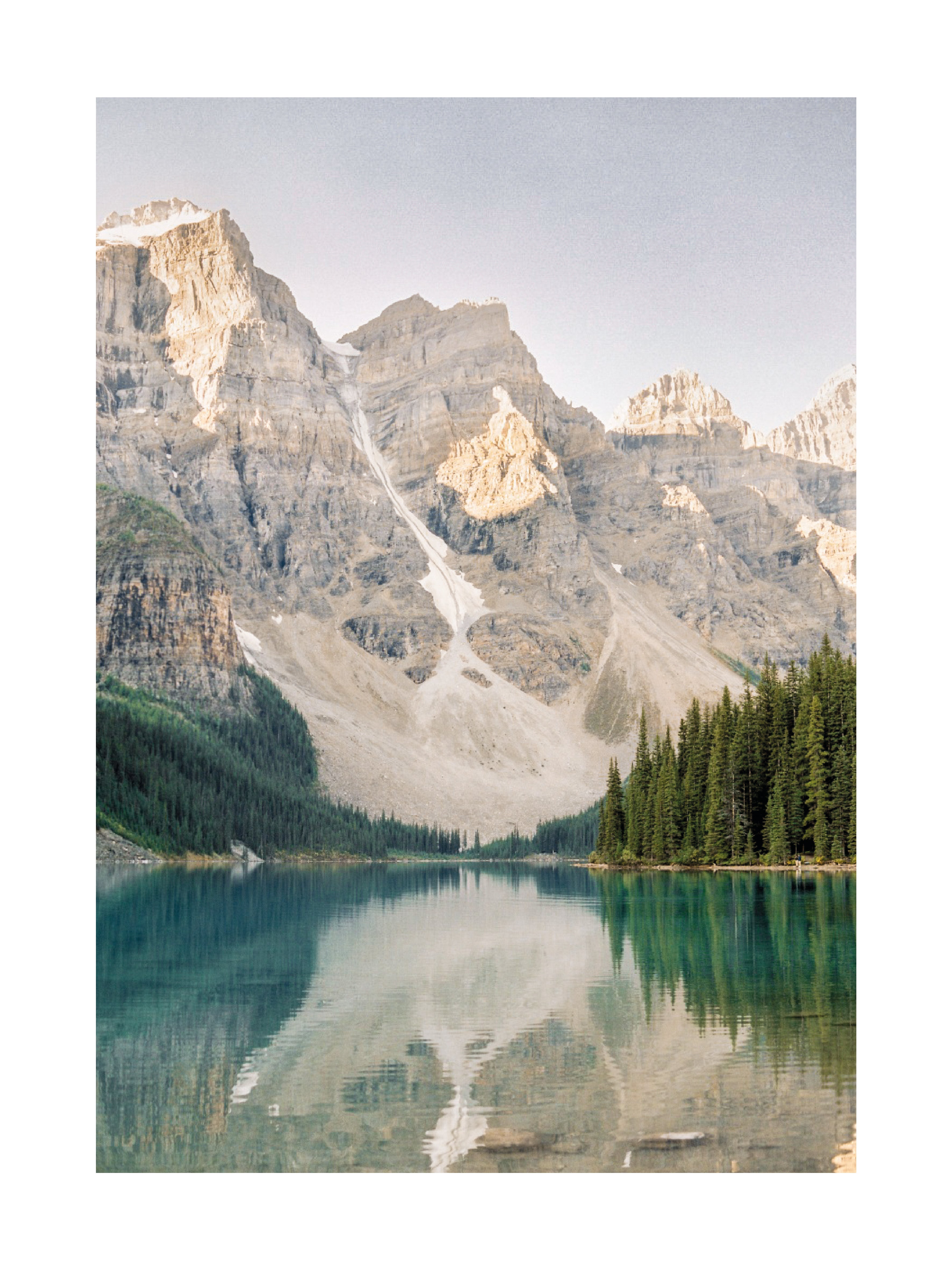 Fotografie des Moraine Lake mit türkisfarbenem Wasser und Bergen im Hintergrund.