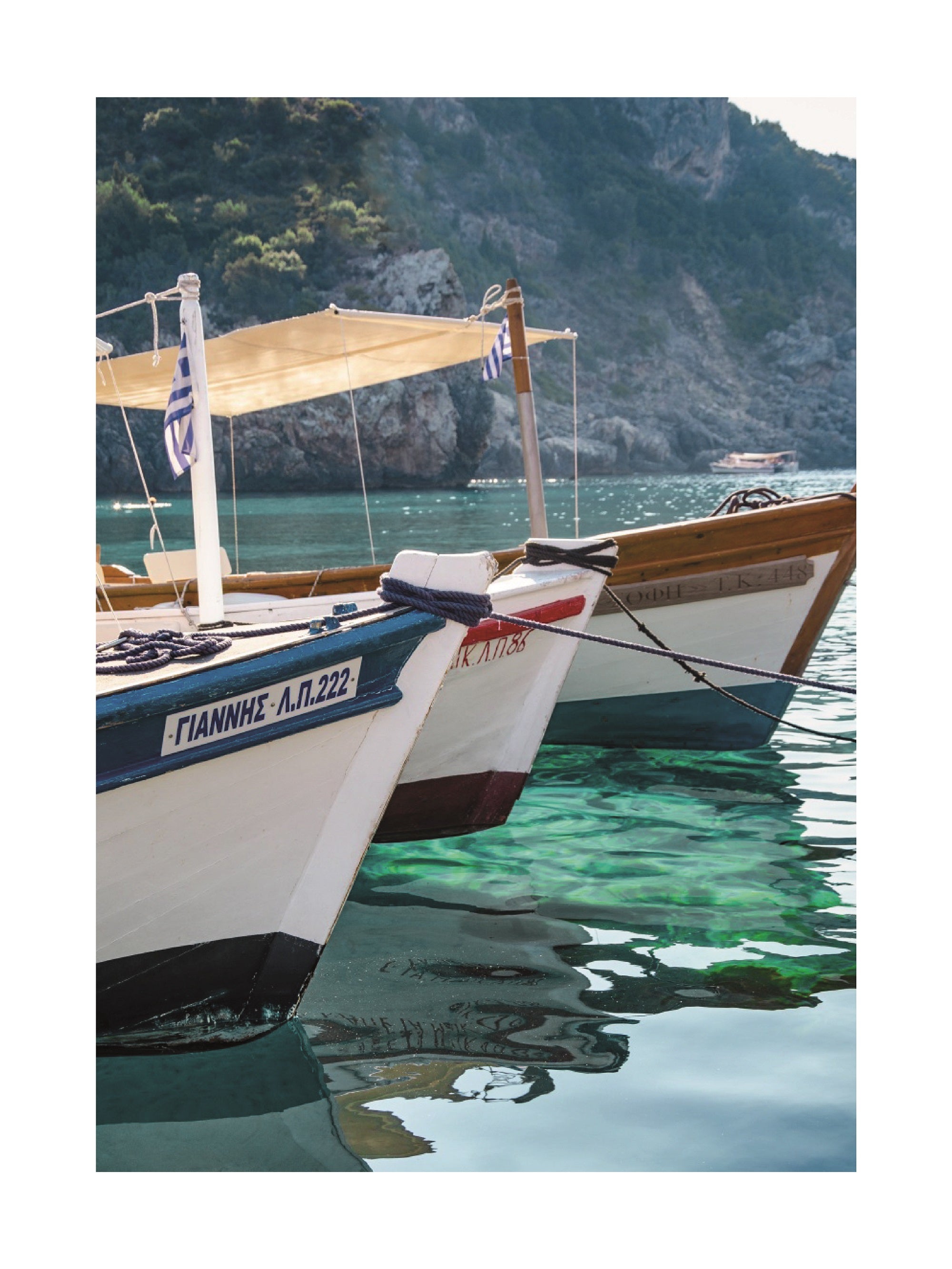 Fotografie von Holzbooten auf dem Wasser mit grünen Bergen im Hintergrund.