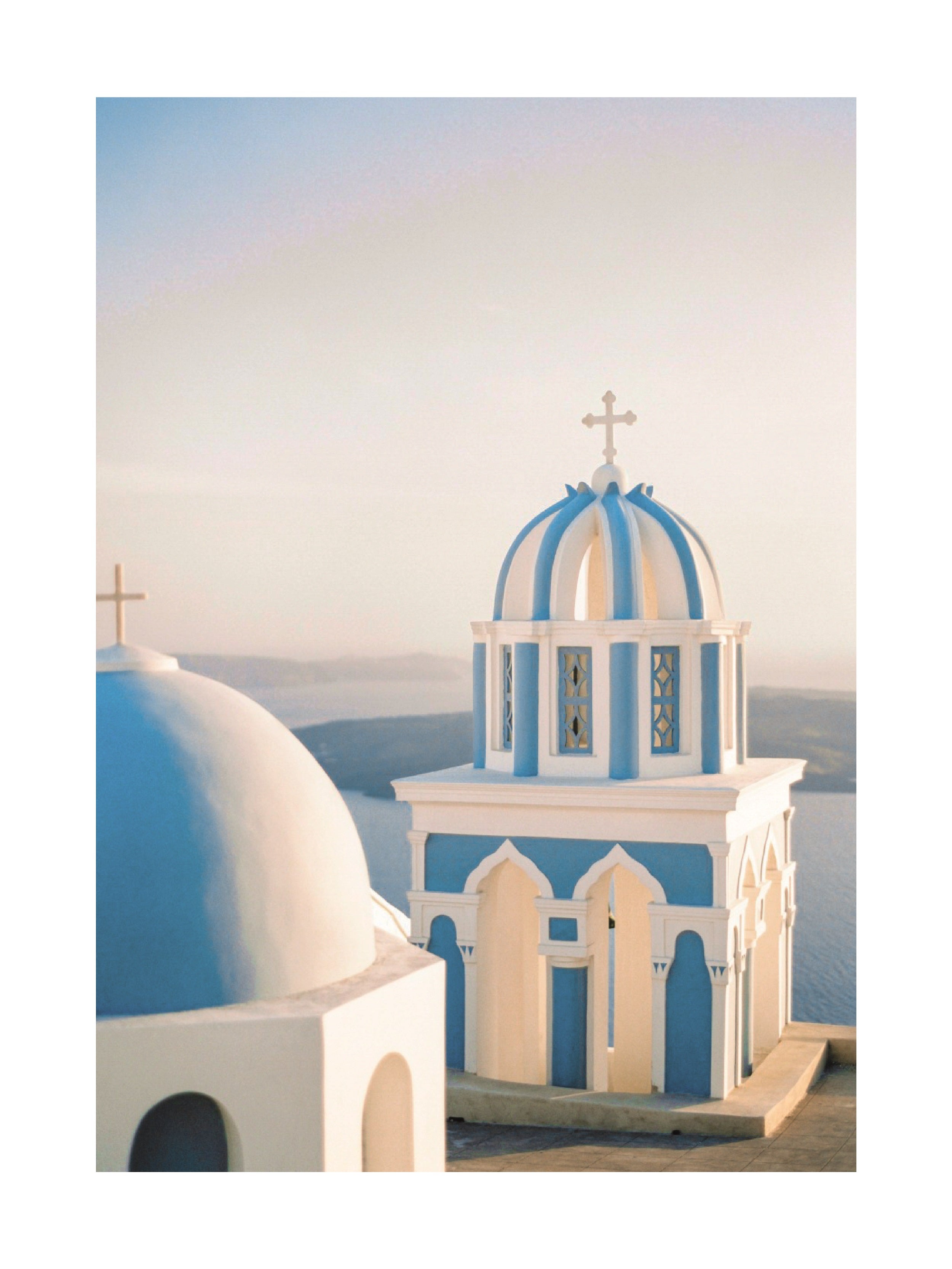 Fotografie von zwei blauen und weißen Kirchtürmen mit Kreuzen auf Santorini.