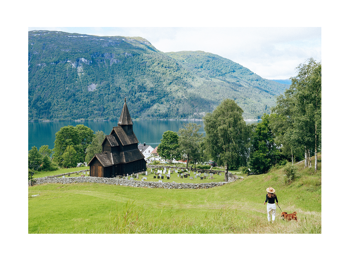 Fotografie der Urnes Stabkirche in Norwegen mit umliegender Landschaft.