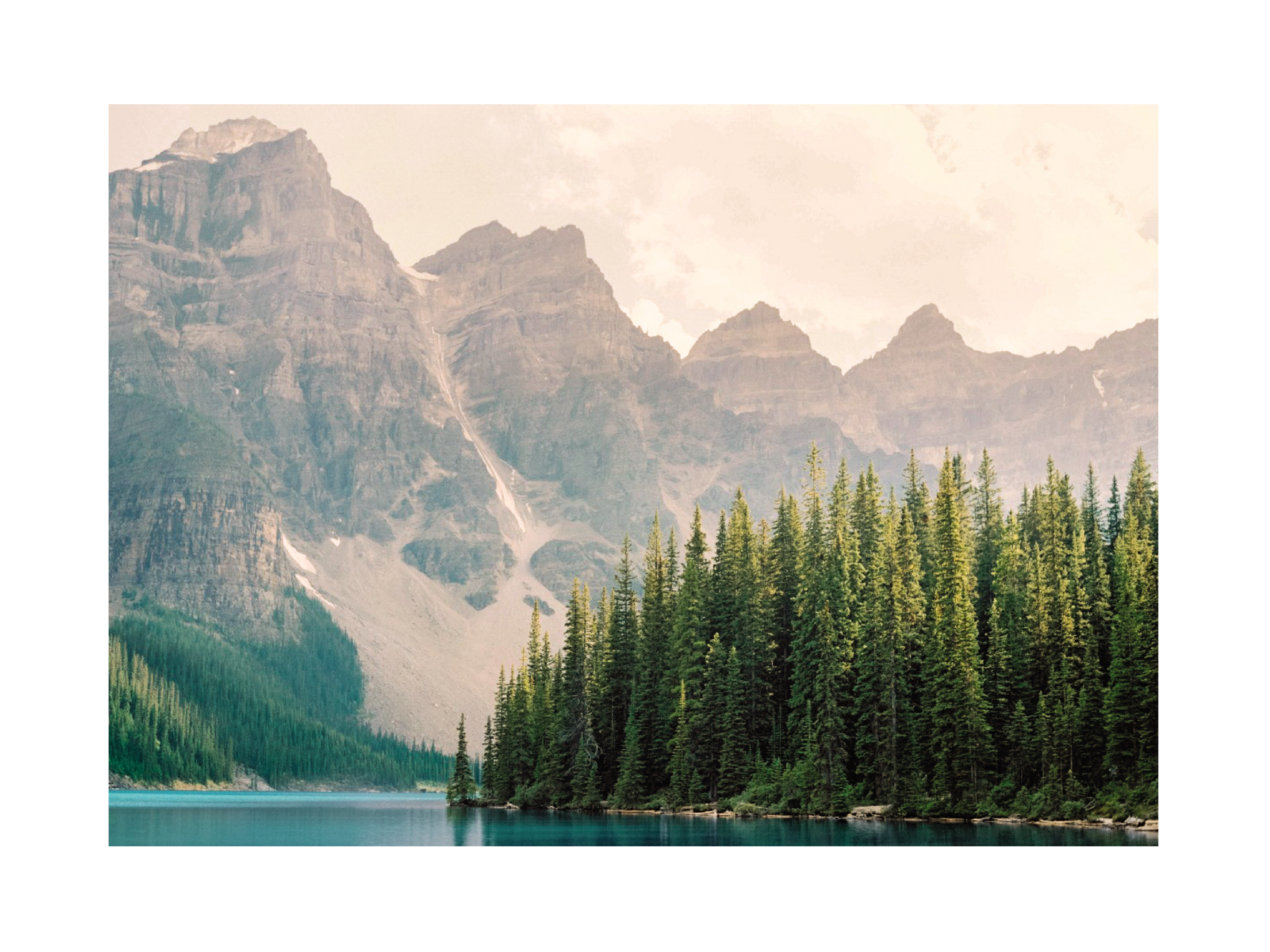 Fotografie des Moraine Lake mit türkisblauem Wasser, grünen Bäumen und Bergen im Hintergrund.