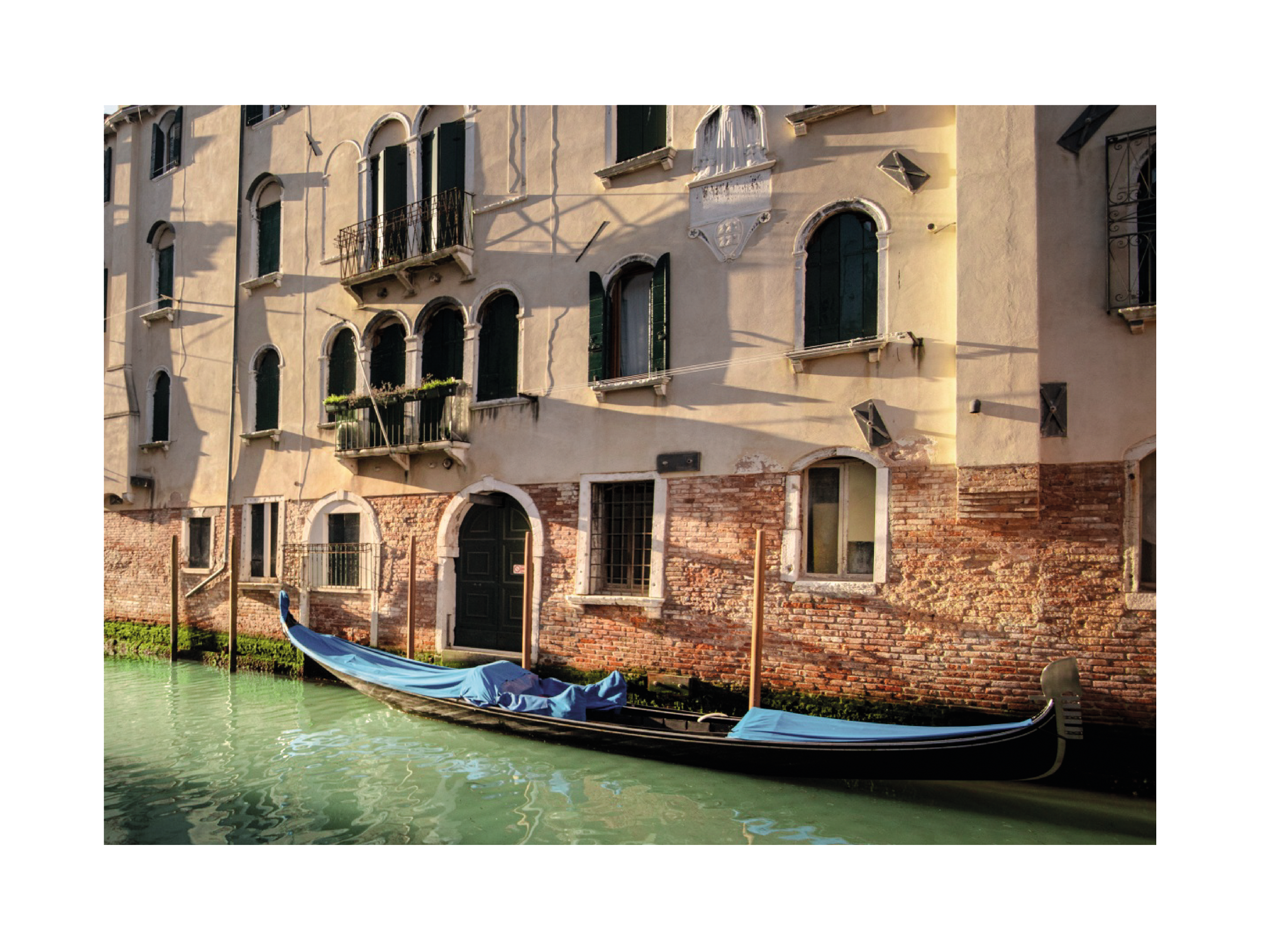 Gondel im Kanal von Venedig vor einer Backsteinfassade.
