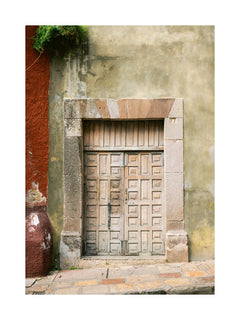 Alte Holztür zwischen einem roten und einem beigen Gebäude.