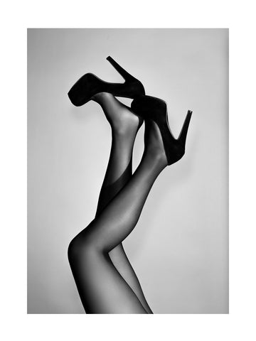 Schwarzweiß-Fotografie von Beinen in High Heels und Strumpfhosen.