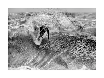 Schwarz-weiß-Fotografie eines Surfers auf einer Welle.
