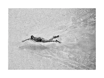Schwarzweiß-Fotografie einer Frau, die in einem Pool schwimmt.