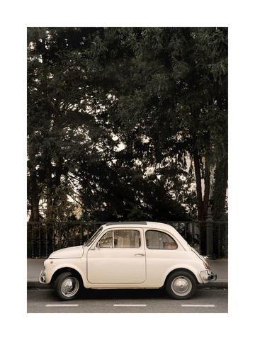 Ein cremefarbenes Auto vor einem grünen Baum.