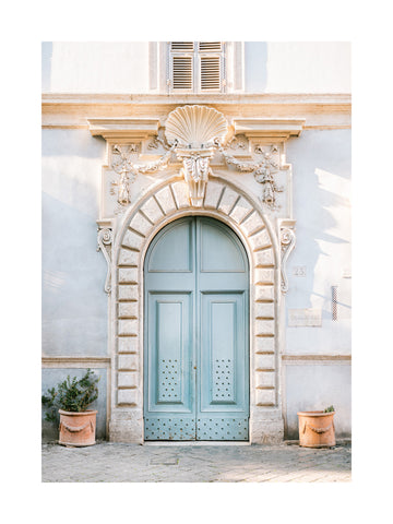 Fotografie einer blauen Tür mit dekorativer Architektur und Pflanzen in Terrakottatöpfen.
