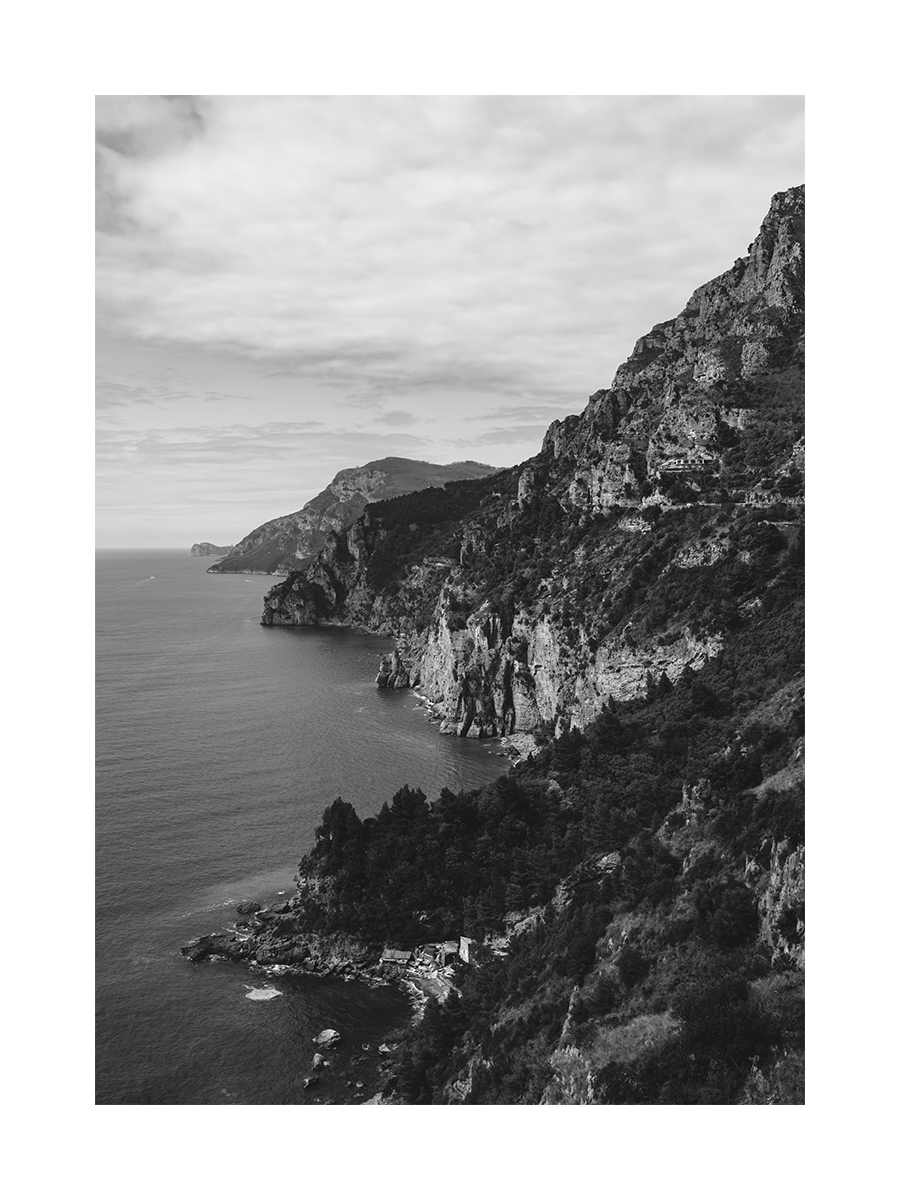 Schwarz-weiß-Fotografie von Klippen und Meer an der Amalfiküste mit bewölktem Himmel.