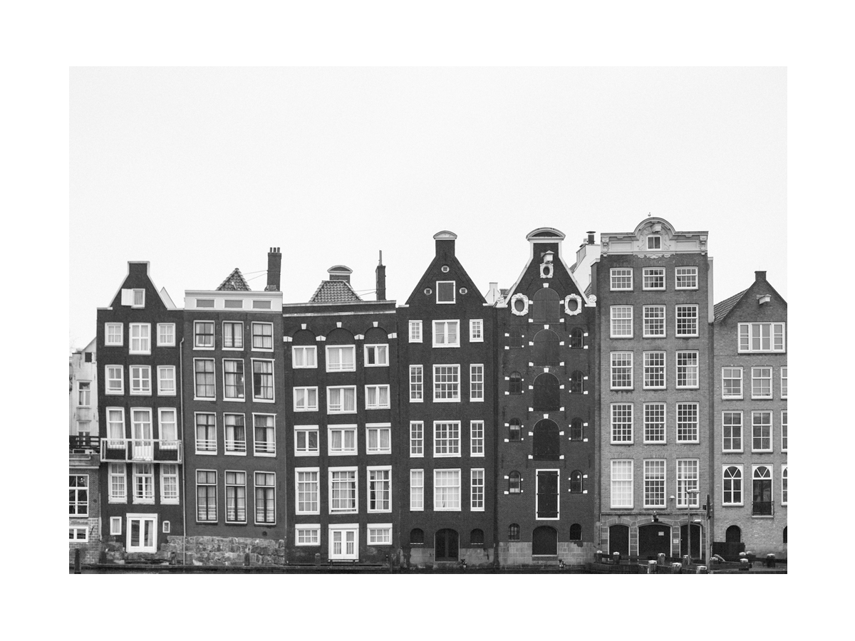 Schwarz-weiße Fotografie von Amsterdamer Giebelhäusern am Wasser.