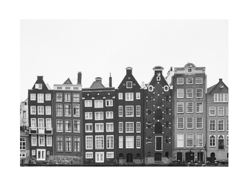 Schwarz-weiße Fotografie von Amsterdamer Giebelhäusern am Wasser.