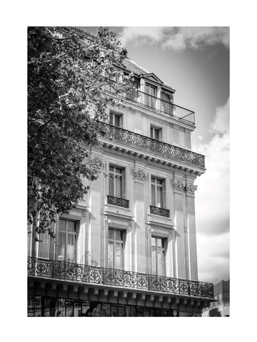 Schwarz-weiß Fotografie eines mehrstöckigen Pariser Gebäudes mit Balkonen und Bäumen.