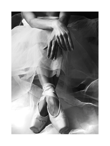 Schwarzweiß-Fotografie einer Ballerina im Tutu mit Ballettschuhen.