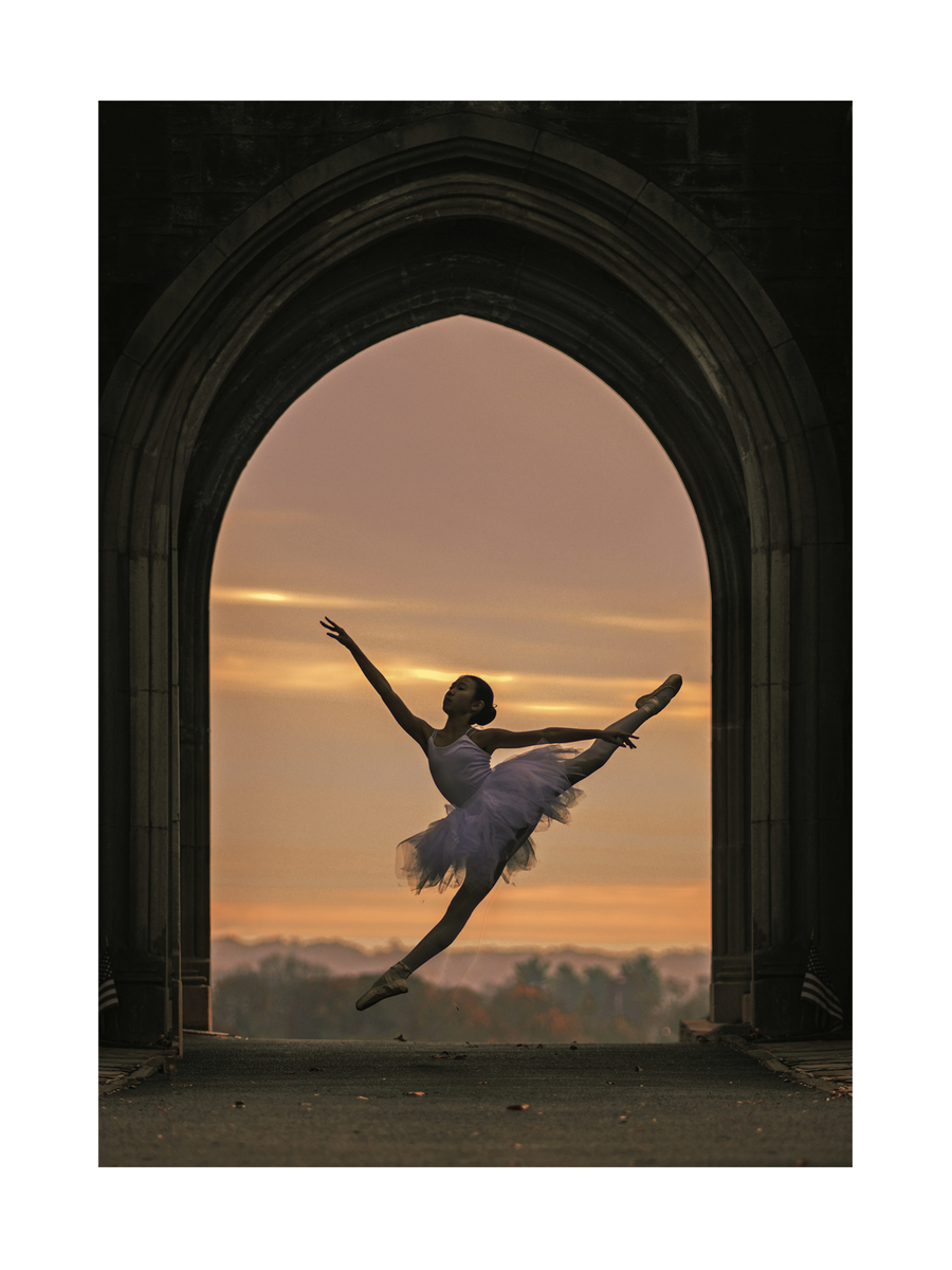 Ballerina im Sprung vor einem Sonnenuntergang, eingerahmt von einem gotischen Torbogen.