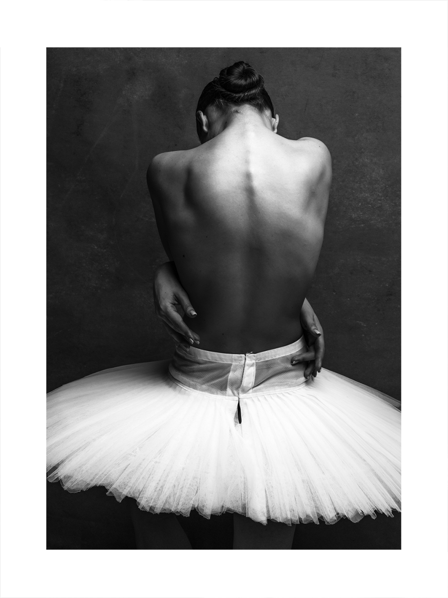 Schwarz-weiß-Fotografie einer Ballerina im Tutu, die ihren Rücken zeigt.