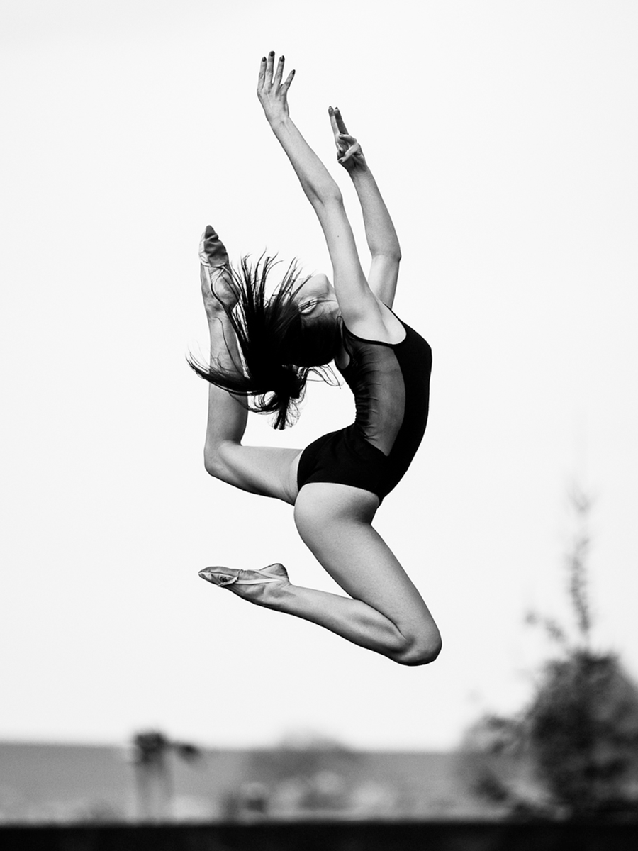 Schwarz-weiß-Fotografie einer Ballerina in einem Sprung.