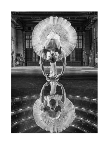 Schwarz-weiß-Fotografie einer Ballerina, die sich auf der Bühne nach vorne beugt und sich im Boden spiegelt.