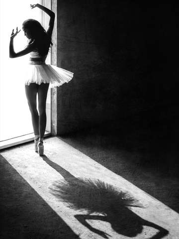Schwarz-Weiß-Fotografie einer Ballerina im weißen Tutu, die einen Schatten auf den Boden wirft.