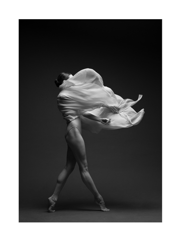 Schwarz-Weiß-Foto einer Balletttänzerin in Bewegung mit fließendem Stoff.