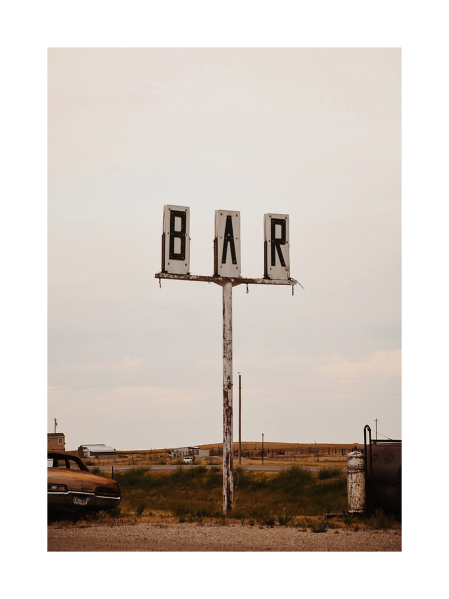 Fotografie eines alten Bar-Schildes in einer ländlichen Gegend.