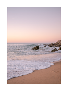 Fotografie eines Sonnenuntergangs am Strand mit Wellen, die den Sand berühren.