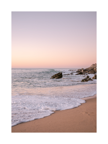Fotografie eines Sonnenuntergangs am Strand mit Wellen, die den Sand berühren.