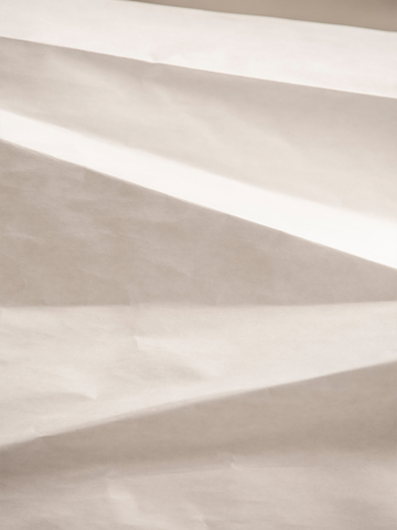 Fotografie von Lichtreflexen auf zerknittertem Papierhintergrund.